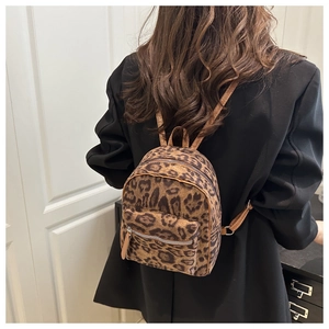 Rear view of a model wearing the leopard print plush mini backpack with leather straps