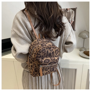 Rear view of a model wearing the leopard print mini backpack with adjustable brown straps