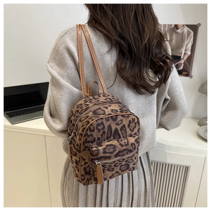 Rear view of a model wearing a mini leopard print backpack with brown leather straps