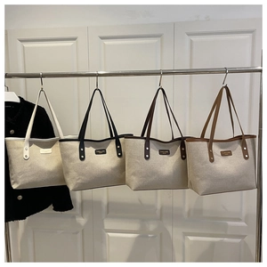 Detail of four canvas tote bags in white, black, brown and tan hanging on a metal rack