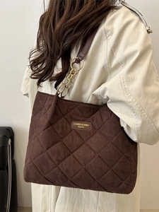 Coffee brown quilted tote bag with chain strap shown on model wearing white trench coat