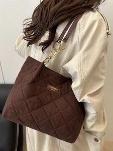 Fashionable dark brown quilted tote bag with chain strap worn by a model in a beige trench coat