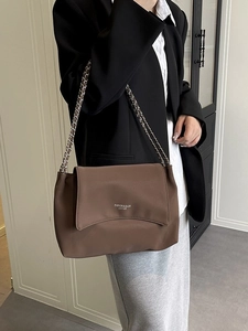 Brown leather tote bag with woven silver chain strap and minimalist text design