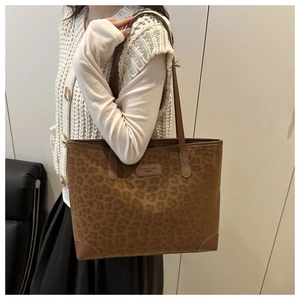 Detail of leopard print faux suede tote bag featuring leather brand label and shoulder strap