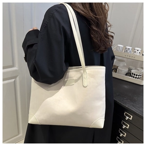 Detail of a creamy white faux suede tote bag with reinforced corners and elegant logo plaque