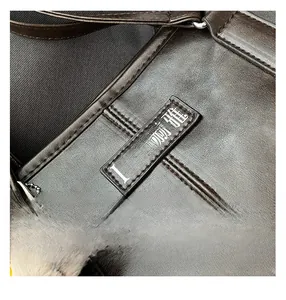 Detail of dark brown leather backpack featuring precision stitching and plush charm