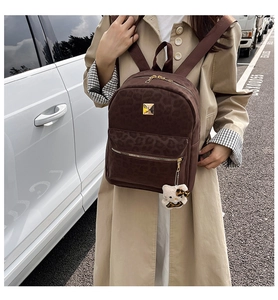 Detail of leopard print backpack with gold metal hardware and plush kitty charm