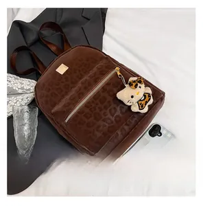 Detail of leopard print backpack featuring gold zippers and a cute character plush pendant