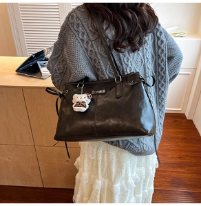Detail of retro black PU leather tote bag with soft texture and side drawstring