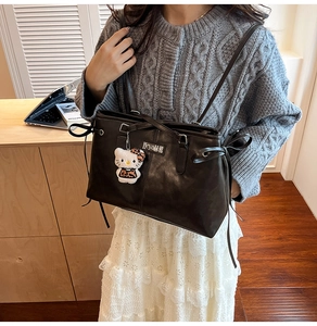Detail of dark brown vintage PU leather tote bag with drawstring bows and plush charm