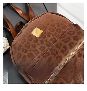 Detail view of leopard print backpack with gold metal hardware and zipper pocket