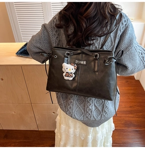 Detail of black faux leather backpack with metal buckle and plush leopard charm