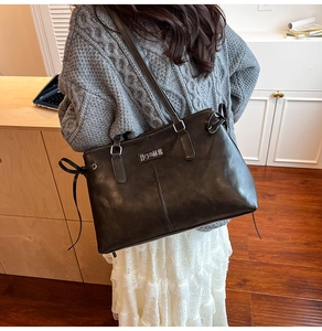 Detail of vintage black PU leather shoulder bag with side bow accents and long straps
