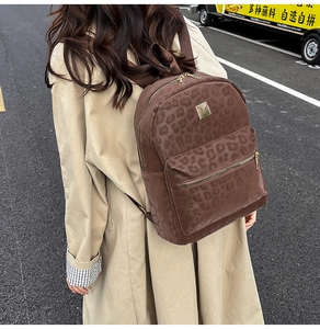Outdoor street view of a casual leopard print backpack with golden metal zippers