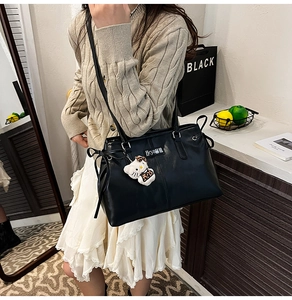 Detail view of black PU leather backpack featuring side bows and leopard print cat charm