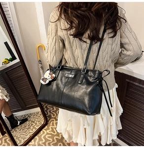 Close-up of black PU leather backpack with silver logo and leopard Hello Kitty charm