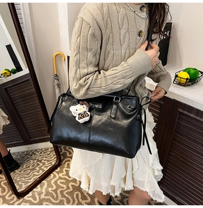 Detail of black PU leather shoulder bag featuring side drawstrings and leopard plush charm