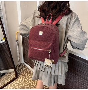 Detail of burgundy leopard print backpack with plush charm and golden square buckle decoration