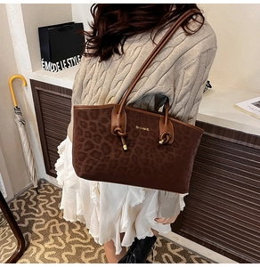 Détail du sac à bandoulière léopard avec nœud décoratif porté par un mannequin chic