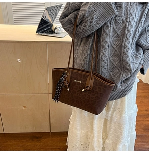Vue détaillée du sac sous le bras à motif léopard avec logo doré et charme tressé