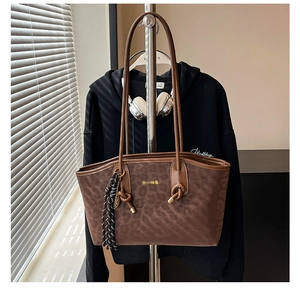 Détail du sac cabas à imprimé léopard avec logo doré, breloque pompon et anses en cuir