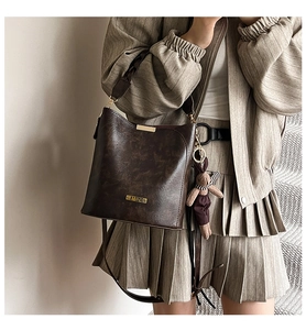 Close-up of vintage dark brown crossbody bucket bag with gold hardware and bear charm