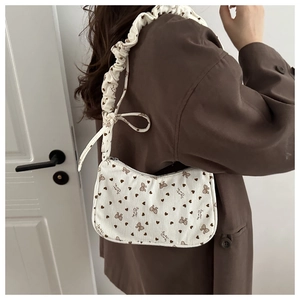 Close-up of corduroy shoulder bag with bow prints and ruffled cloud-style strap