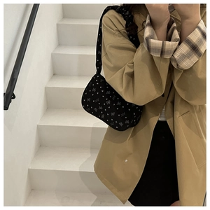 Model wearing a black floral crescent bag with heart prints over a trench coat