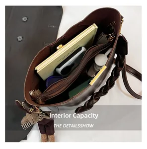 Detail view of the brown bucket bag interior capacity with compartments and woven handle