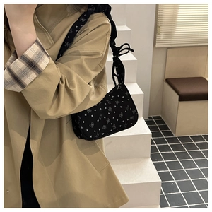 Detail of floral dumpling bag with heart and bow patterns worn by a model in a trench coat