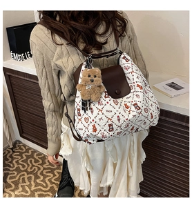 Detail view of cream textured backpack featuring cartoon prints and a plush bear charm