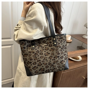 Detail of leopard print tote bag with black leather straps and gold metal hardware