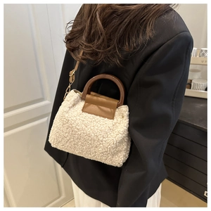 Seitenansicht der weißen Teddy-Handtasche mit braunen Rundgriffen und Schultergurt