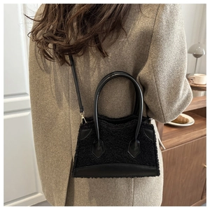 Detail of black faux fur mini bag featuring smooth leather handles and long shoulder strap