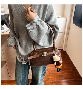 Close-up of brown leopard print suede handbag with metal buckle and plush charm detail