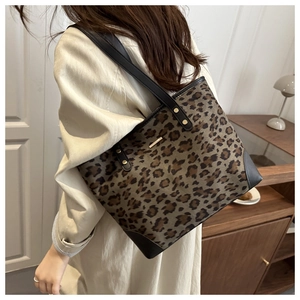 Close-up of leopard print tote bag featuring black leather handles and metal logo detail