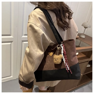 Detalle de bolso bucket bicolor con colgante de oso de peluche y cuerda trenzada en ante