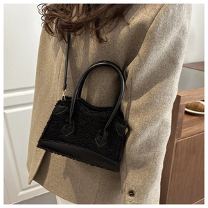 Detail of black faux fur handbag with leather straps worn as a stylish crossbody bag