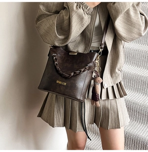 Close-up of vintage dark brown bucket bag with woven chain and cute teddy bear pendant