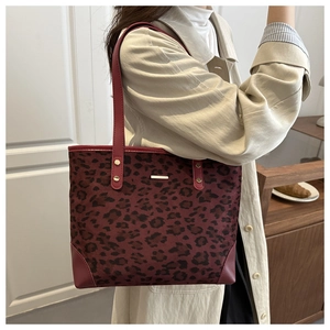 Detail of dark red leopard print tote bag with wine red leather straps and gold rivets