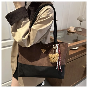Detail of vintage tote bag with bicolor suede finish and bear charm on a model
