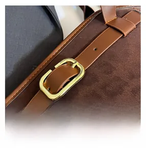 Macro shot of gold buckle and premium stitching on dark brown suede handbag strap