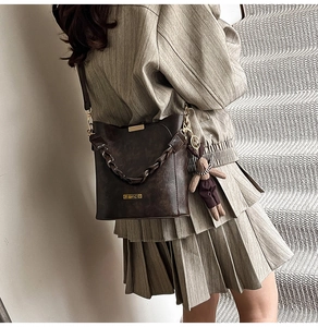 Detail of dark brown bucket bag with gold HEVADO logo and cute bunny pendant