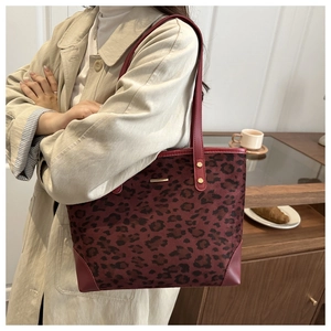 Detail view of burgundy leopard print tote bag with gold metal accents and reinforced straps