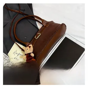 Detail of dark brown leopard print handbag with leather strap and plush cat charm