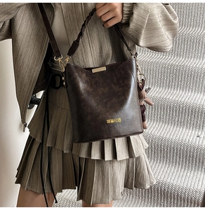 Detail of vintage brown bucket bag with woven handle and cute bear charm accessory