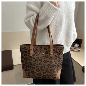 Detail of leopard print tote bag with brown faux leather trim and gold metal logo bar