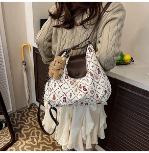 Detail view of white quilted tote bag featuring cartoon bear prints and brown leather strap