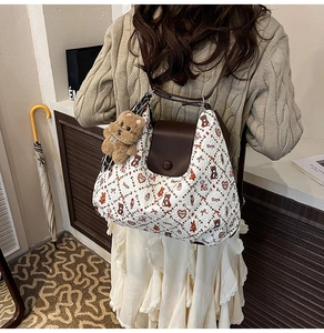 Detail of off-white fabric tote with brown leather flap and cute plush dog charm