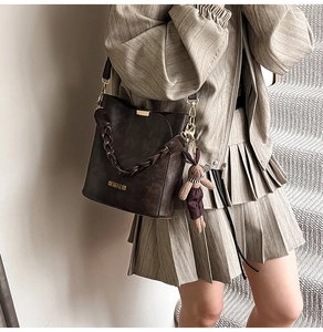Detail of dark brown vintage leather bucket bag with woven handle and bunny charm